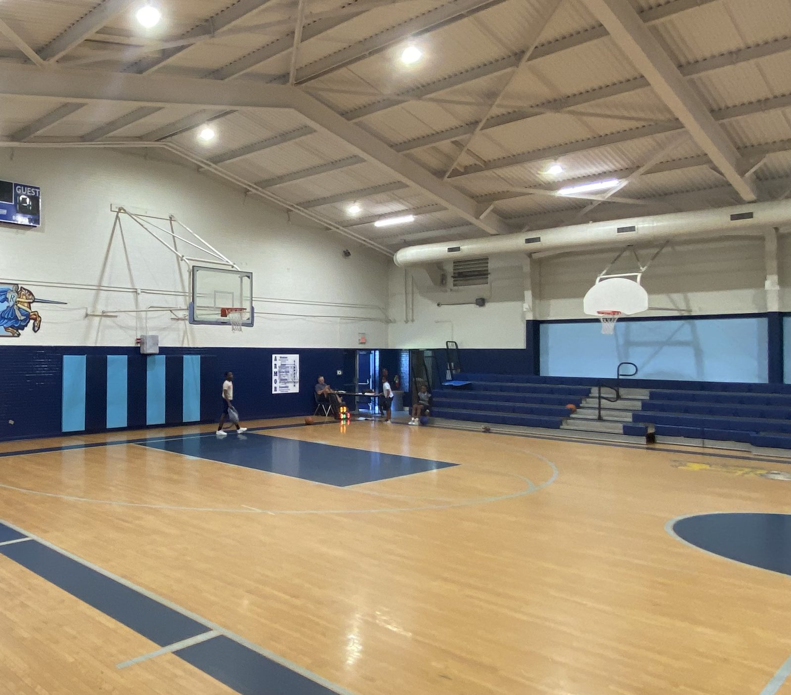 Community center gym with the wood floor refinished, bleachers in place and the lights on, back in use