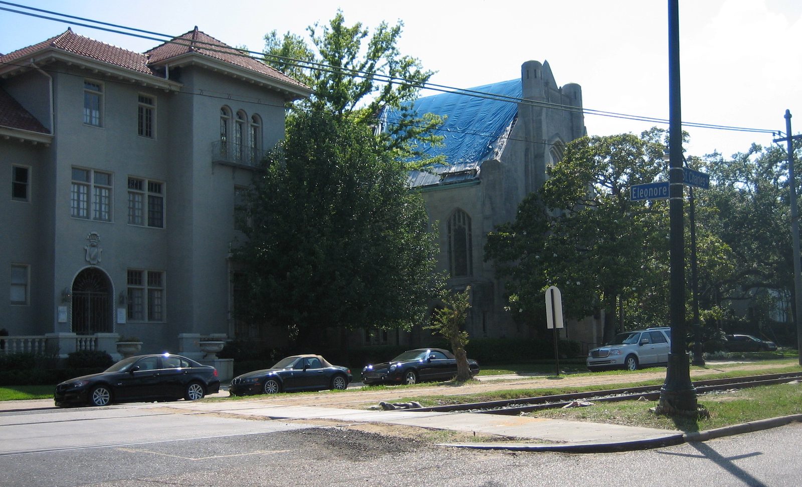 Stone church with a blue tarp covering the storm-damaged roof, seen from across the street